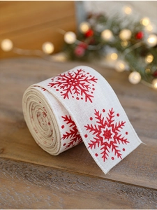 Close-up of beige linen ribbon with red glitter snowflake prints on wood surface