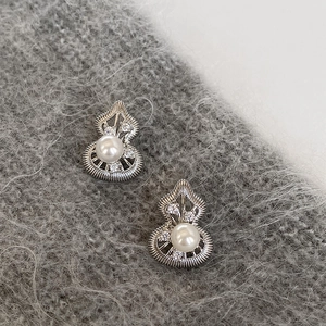 Macro shot of silver hollow gourd earrings with white pearls and sparkling zircons