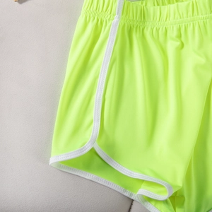 Detail of neon green elastic sports shorts with white contrast piping and curved hem