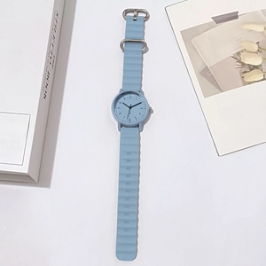Macro detail of a light blue quartz watch with wavy silicone strap on a lifestyle backdrop