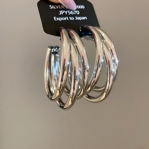 Macro shot of triple-layered silver hoop earrings with a high-shine metallic finish