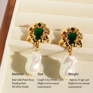 Vintage vine-style emerald drop earrings with iridescent pearls on a beige velvet tray