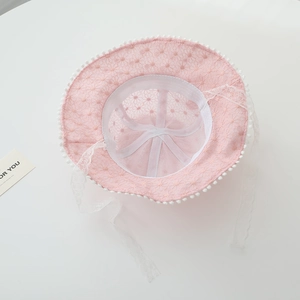 Detail of baby girl pink lace sun hat featuring white pom-poms and delicate floral mesh