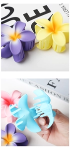 Detail showing various colors of plastic plumeria flower hair claws in a high-quality close-up