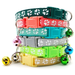 Detailed stack of nylon pet collars with white paw prints and colorful bells