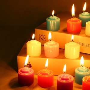 Detailed view of colorful tea light candles burning on books for warm home decor