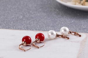 Gros plan de boucles d'oreilles perles rouges et blanches avec crochets en or rose
