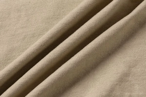 Detailed macro view of the soft beige knitted fabric texture and fine stitching pattern