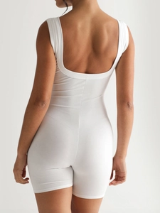 White ribbed one-piece yoga jumpsuit for women shown from the back in a studio setting