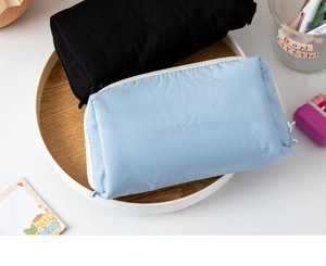 Close-up of minimalist black and light blue zippered mesh stationery pouches on a tray