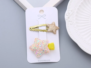 Detail showing glitter star hair clips set with gold sequins and yellow ribbon wrap