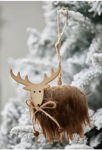 Detail of wooden reindeer ornament with fur finish hanging on a snowy Christmas tree