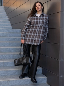Close-up of brown plaid patchwork shirt styled with black leather pants and a handbag