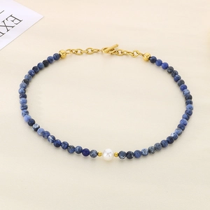 Macro view of blue spotted stone beads and white pearl detail with golden OT clasp