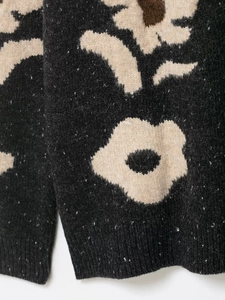 Detail eines Blumen-Jacquard-Strickpullovers mit dickem schwarzem Stoff und Textur