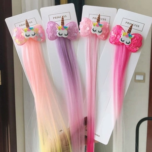 Detail of four colorful unicorn sequin bow hair clips with long hair extensions on card
