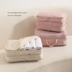 Cubes de compression rose et beige pour vêtements posés sur un canapé en tissu