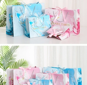 Detail of marble pattern gift bags in blue and pink with golden dots and silk ribbons