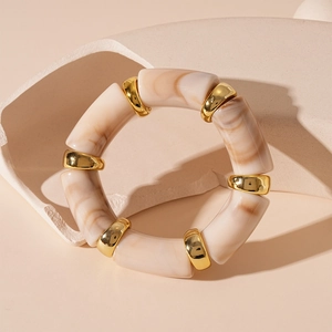 Detail of beige marble resin bamboo segments and gold metal rings on a stone stand