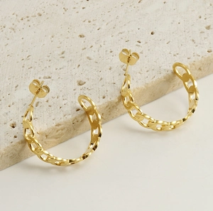 Detail of 18k gold plated stainless steel interlocking chain link hoop earrings on stone