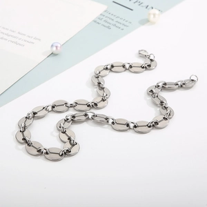 Close-up of a silver coffee bean link chain in a stylish S-curve layout with pearls
