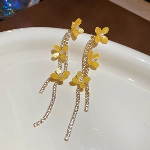 Close-up of yellow resin flower earrings with silver tassel and rhinestone details