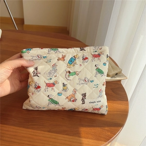 Close-up of quilted cotton cosmetic bag featuring cute cartoon dog prints and side label