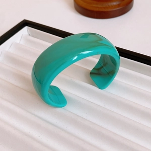 Close-up of chunky green marble resin cuff bracelet on a white display tray
