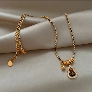 Macro detail of 18K gold gourd pendant with tiger eye stones and pavé set crystals