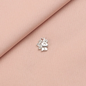 Polished silver stainless steel dinosaur charm for DIY jewelry on pink fabric background