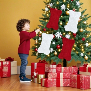 Boy hanging bone-shaped knitted Christmas stockings on tree with red and white festive decor
