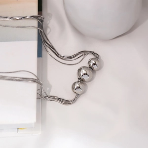 Detailed view of layered silver snake chains with three polished metallic sphere pendants