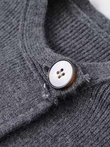 Close-up of a grey rib-knit cardigan coat featuring a premium amber resin button detail