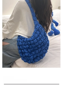 Detail of royal blue pleated cloud bag showing the textured bubble fabric and shoulder strap