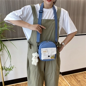 Détail du sac en toile bleu et blanc avec écusson nuage et pendentif ours peluche