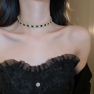 Gros plan du collier choker de luxe avec cristaux noirs et clairs sur monture dorée