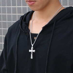 Close-up of a double-layered polished silver cross pendant on a rope chain for men