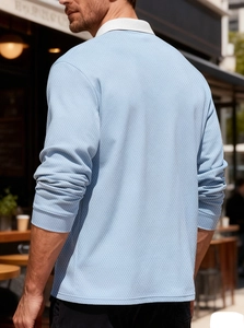 Detail of light blue men's polo shirt showing textured honeycomb knit and white collar
