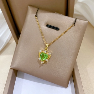 Close-up of heart green gemstone necklace with pavé diamonds in a beige jewelry box