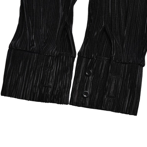 Detailed close-up of ruffle cuff texture and button design on black casual shirt