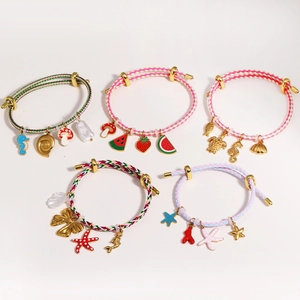 Adjustable woven bracelet set with gold charms and marine pendants on white background