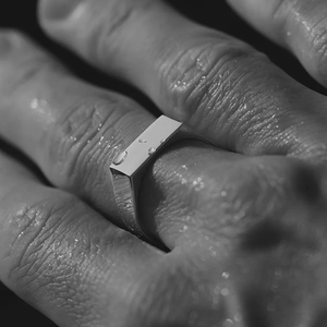 Polished silver stainless steel rectangular band ring with water droplets on hand
