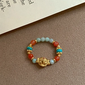 Detailed macro view of beaded ring featuring red agate, turquoise, and golden fox charm
