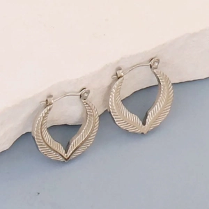 Silver stainless steel geometric hoop earrings with feather texture on a rock