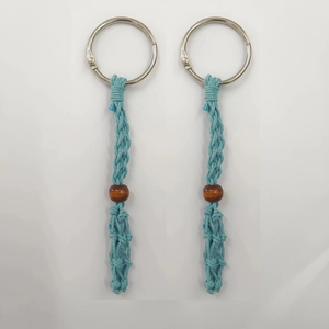 Détail du porte-clés tressé bleu clair avec perle en bois marron naturel et anneau métallique