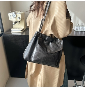 Dettaglio della borsa tote nera con catena in metallo e tasca mostrata su una modella