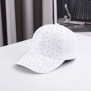 Detail view of a white baseball cap featuring floral lace texture and rainbow rhinestones