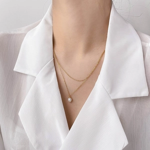 Close-up of a double-layer gold chain necklace with an elegant white pearl pendant