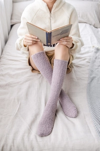 Cosy purple coral fleece knee-high socks for women shown in a warm home setting