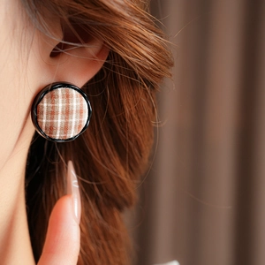 Close-up of brown plaid fabric round stud earrings on a model with vintage aesthetic